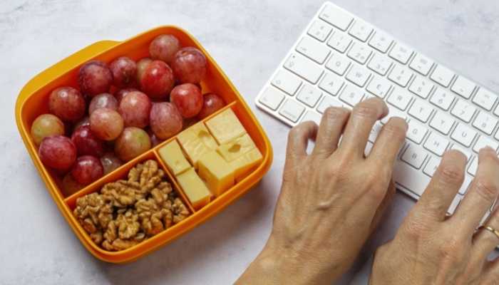 Pessoa com teclado e frutas num Tupperware