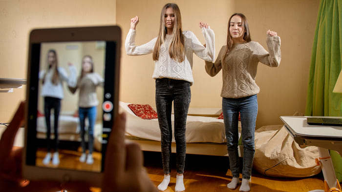 Gravação de vídeo em smartphone de duas adolescentes dançando para postagem na internet. Comunicação moderna, mídias sociais e gadgets